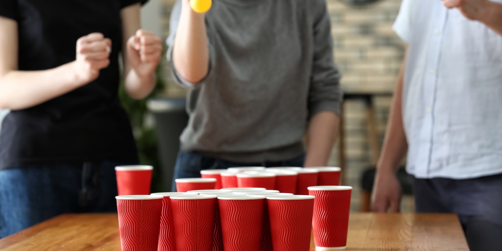 college students play beer pong as part of beer drinking
