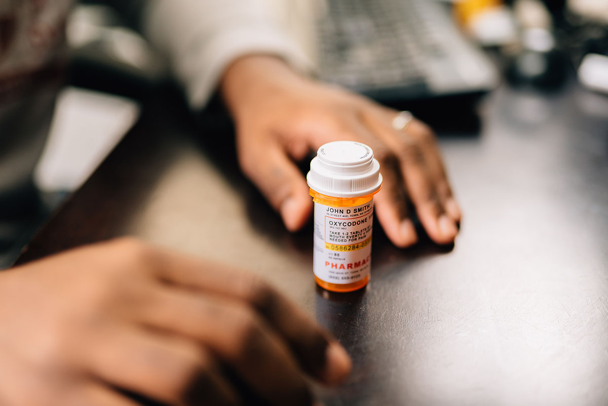 a person with an opioid addiction stares at a bottle of pills