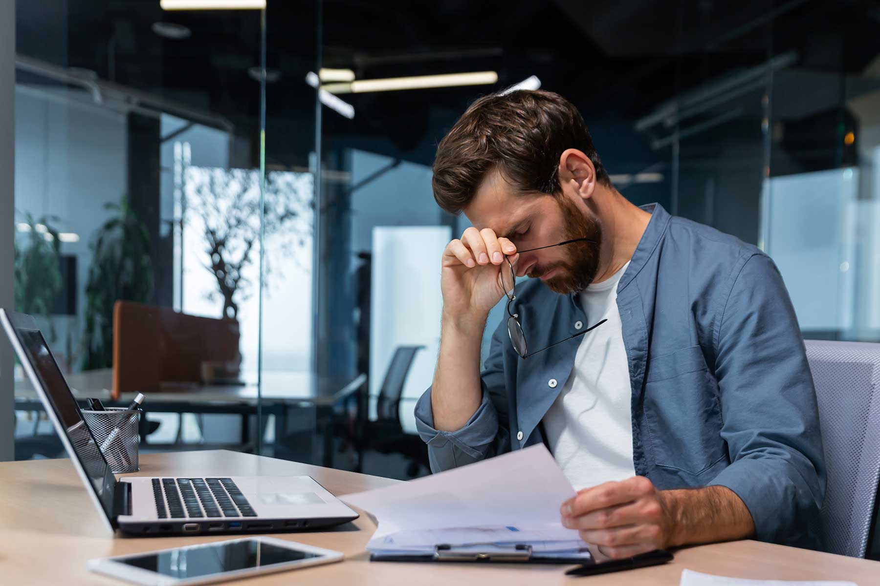 Man at work with a headache suffering from post-acute withdrawal syndrome